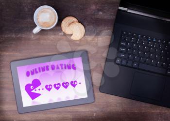 Online dating on a tablet - concept of love, purple pacman eating hearts