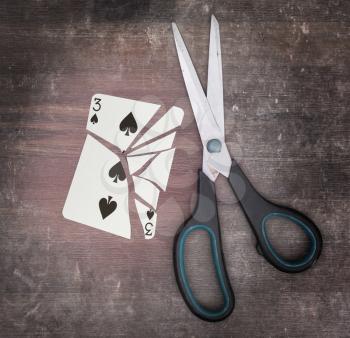 Concept of addiction, card with scissors, three of spades