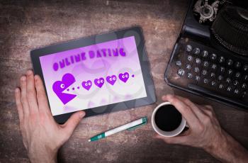 Online dating on a tablet - concept of love, purple pacman eating hearts