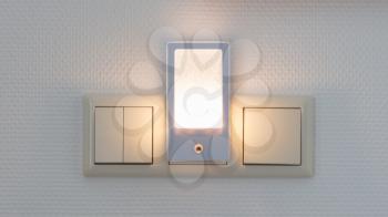 Plastic nightlight illuminating the wall and light switch
