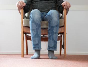 Man sitting in armchair, slightly creepy setting