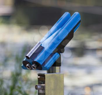Blue coin operated fixed binoculars in a park