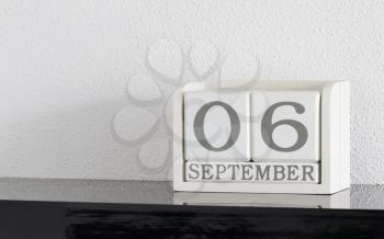 White block calendar present date 6 and month September on white wall background