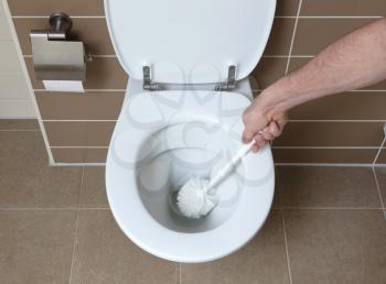 Modern white toilet bowl in the bathroom, cleaning with toiletbrush
