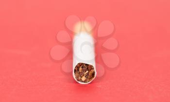 Single cigarette isolated on red background, selective focus