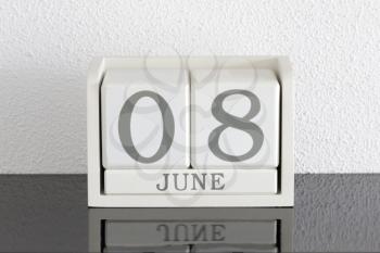 White block calendar present date 8 and month June on white wall background