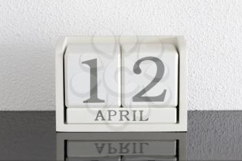 White block calendar present date 12 and month April on white wall background