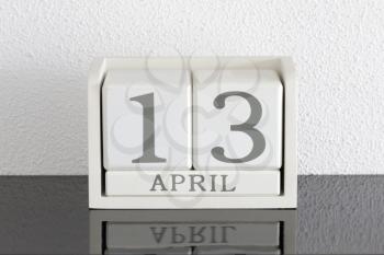 White block calendar present date 13 and month April on white wall background