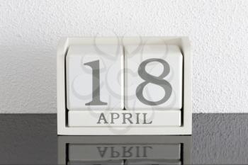 White block calendar present date 18 and month April on white wall background