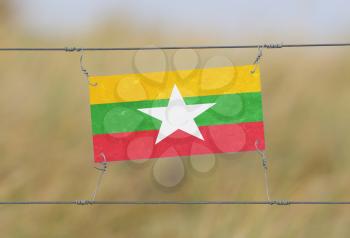 Border fence - Old plastic sign with a flag - Myanmar