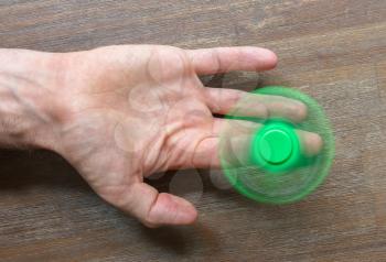 Image of Fidget finger spinner stress toy - Green spinner on a wooden desk