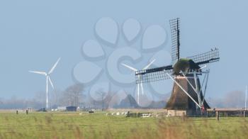 Old windmill with modern windmills in the background - Selective focus - Time has changed