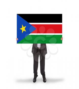 Businessman holding a big card, flag of South Sudan, isolated on white