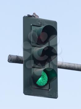 Green traffic light at hanging lamp under blue sky