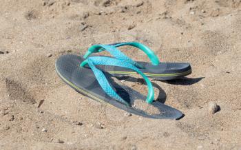 Blue and green flip flops in the sand
