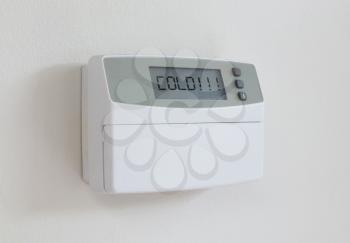 Vintage digital thermostat hanging on a white wall - Covert in dust - Cold