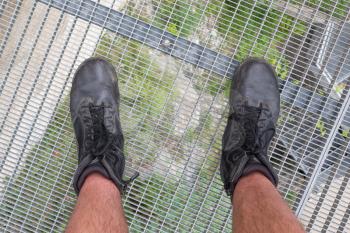 Man standing on a high platform wearing trekking shoe - Depth