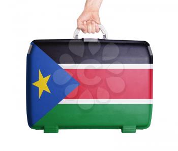 Used plastic suitcase with stains and scratches, printed with flag - South Sudan