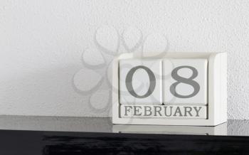 White block calendar present date 8 and month February on white wall background