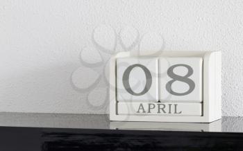 White block calendar present date 8 and month April on white wall background