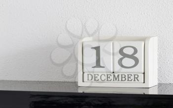 White block calendar present date 18 and month December on white wall background