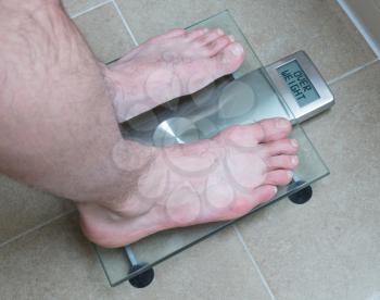 Closeup of man's feet on weight scale - Overweight
