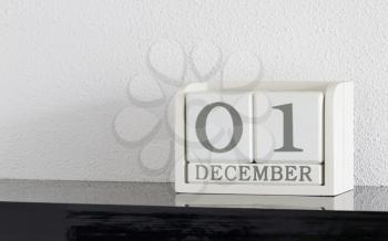 White block calendar present date 1 and month December on white wall background