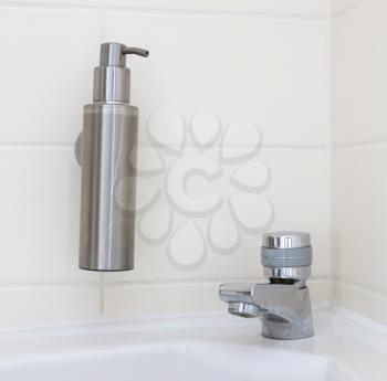 Hand sanitizer dispenser on a white tiled wall