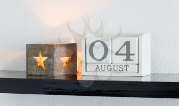White block calendar present date 4 and month August on white wall background