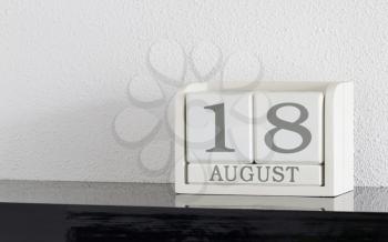 White block calendar present date 18 and month August on white wall background