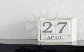 White block calendar present date 27 and month April on white wall background
