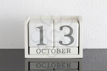 White block calendar present date 13 and month October on white wall background
