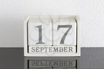 White block calendar present date 17 and month September on white wall background