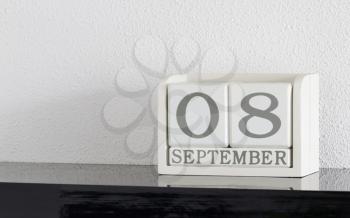White block calendar present date 8 and month September on white wall background