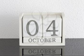 White block calendar present date 4 and month October on white wall background