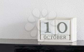 White block calendar present date 10 and month October on white wall background