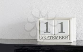 White block calendar present date 11 and month September on white wall background
