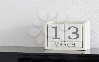 White block calendar present date 13 and month March on white wall background