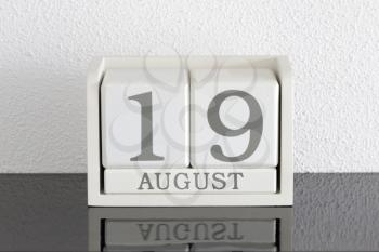 White block calendar present date 19 and month August on white wall background