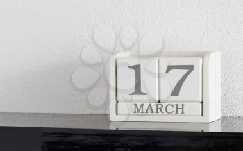 White block calendar present date 17 and month March on white wall background