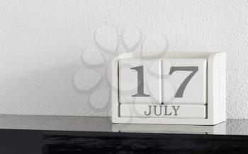 White block calendar present date 17 and month July on white wall background