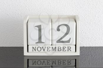 White block calendar present date 12 and month November on white wall background