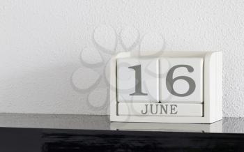 White block calendar present date 16 and month June on white wall background