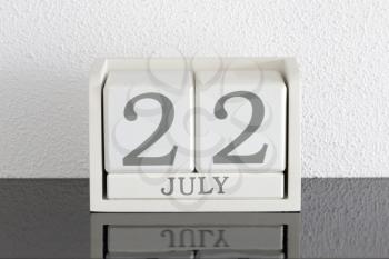 White block calendar present date 22 and month July on white wall background