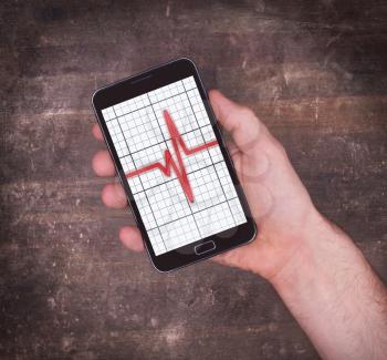 Electrocardiogram on a smartphone - Concept of healthcare, heartbeat shown on monitor - red