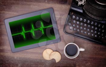 Electrocardiogram on a tablet - Concept of healthcare, heartbeat shown on monitor - green