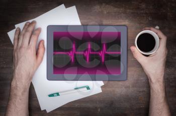 Electrocardiogram on a tablet - Concept of healthcare, heartbeat shown on monitor - pink