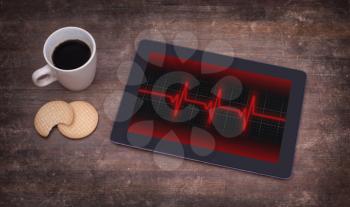 Electrocardiogram on a tablet - Concept of healthcare, heartbeat shown on monitor - red