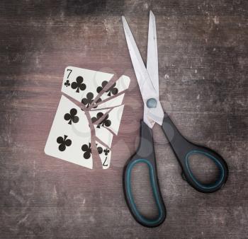 Concept of addiction, card with scissors, seven of clubs