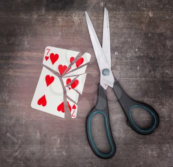 Concept of addiction, card with scissors, seven of hearts